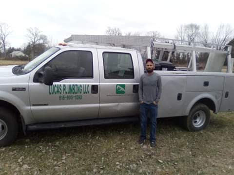 Lucas Plumbing service truck with a plumber standing beside it